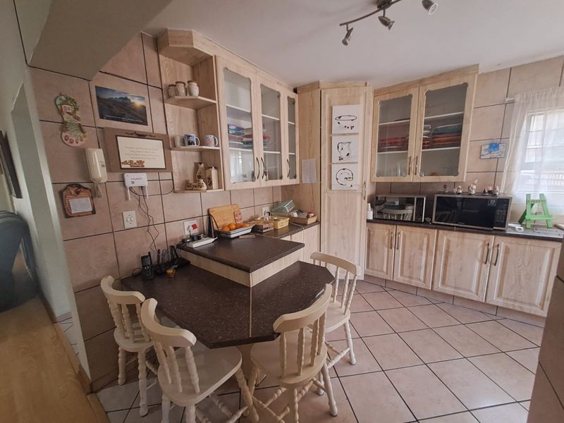 A functional kitchen featuring light wood-finish cabinetry, tiled backsplash, and a built-in breakfast nook with dark countertops.