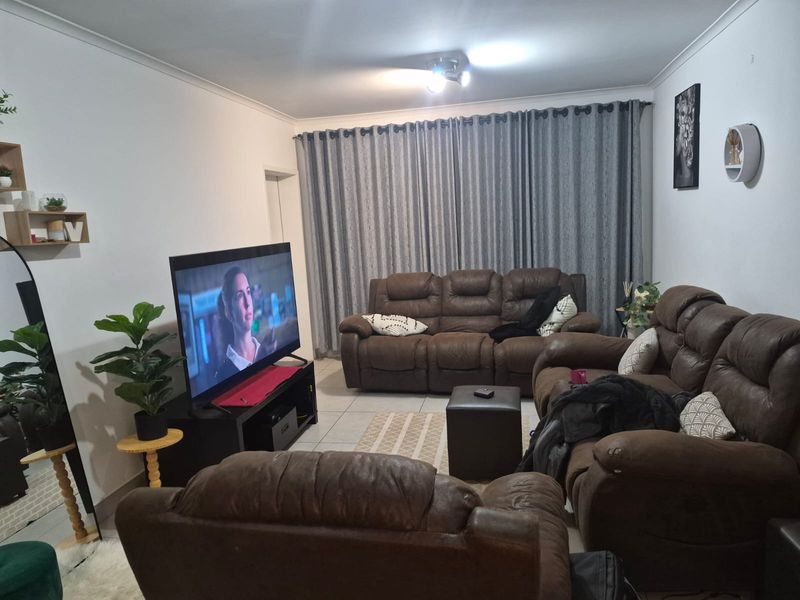 A comfortable living room featuring tiled flooring and neutral wall finishes, providing a functional space for relaxation.