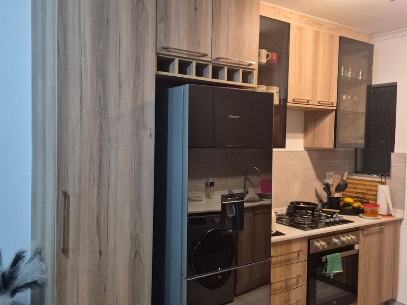 Modern kitchen featuring wood-grain cabinetry, built-in oven, gas hob, and tiled flooring, offering a functional and contemporary cooking space.