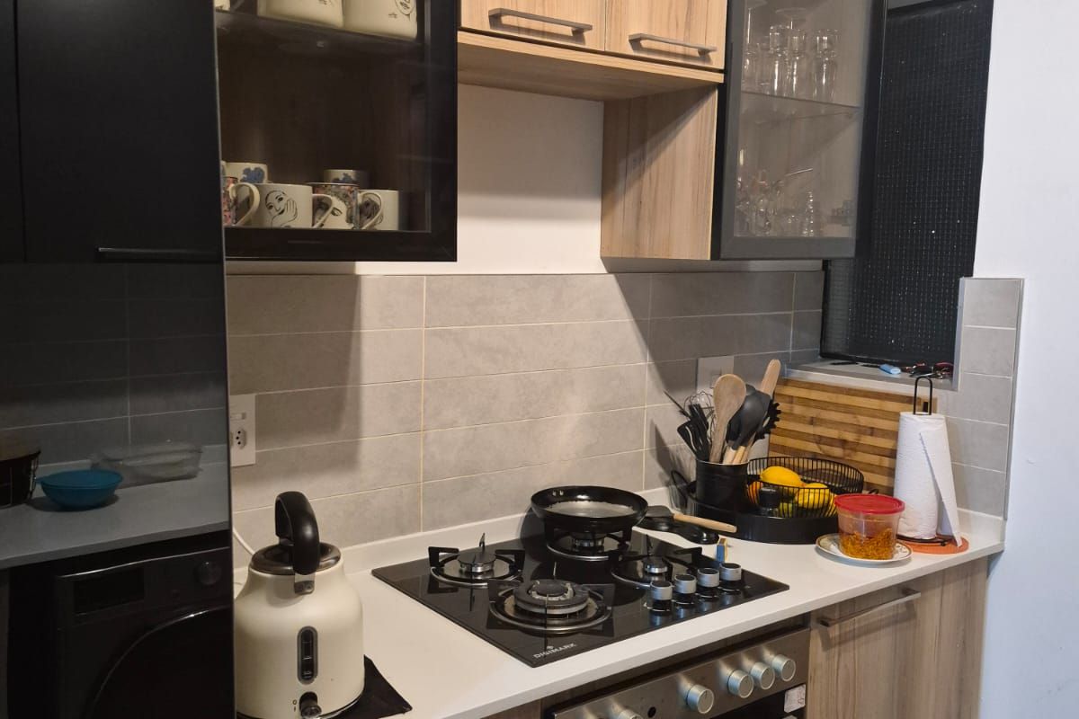 Modern kitchen featuring wood-grain and black cabinetry, stone countertops, a gas hob, and a built-in oven with a tiled backsplash.