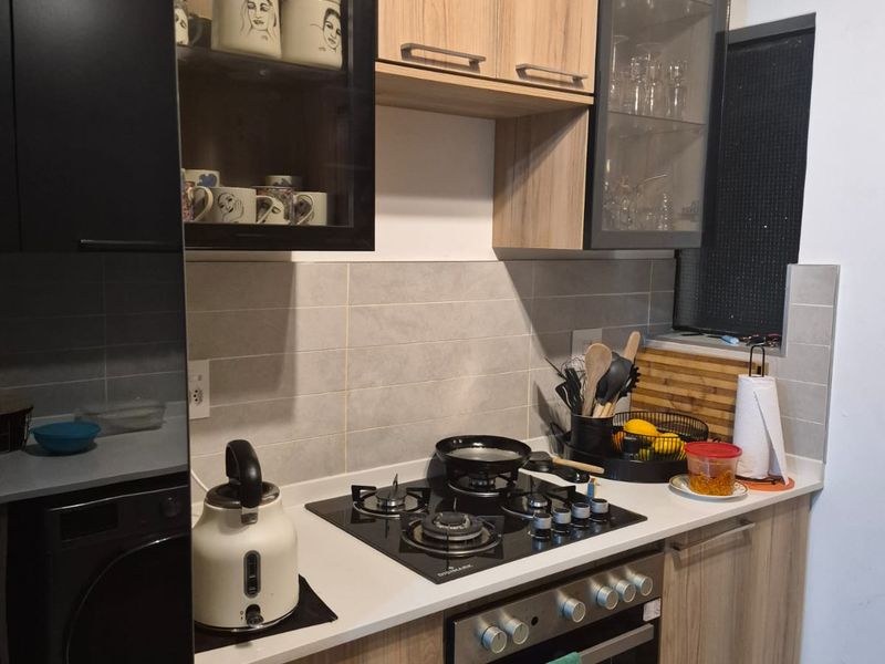 Modern kitchen featuring wood-grain and black cabinetry, stone countertops, a gas hob, and a built-in oven with a tiled backsplash.