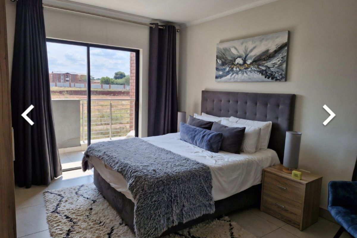 A well-maintained bedroom featuring tiled floors and a sliding glass door that opens onto a private balcony.