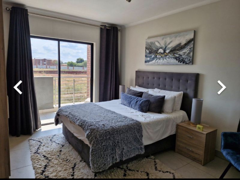 A well-maintained bedroom featuring tiled floors and a sliding glass door that opens onto a private balcony.