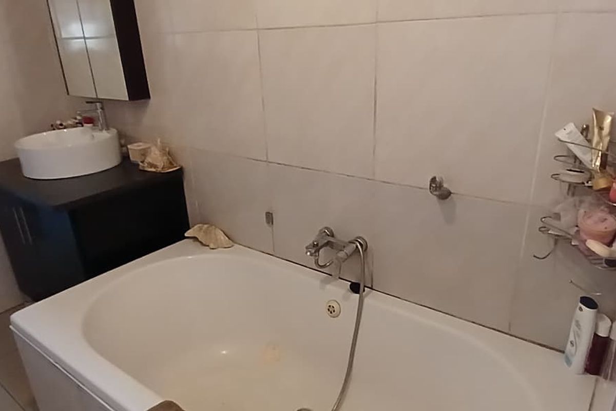 A functional bathroom featuring a built-in vanity with a vessel sink, a bathtub with a handheld shower attachment, and tiled wall finishes.