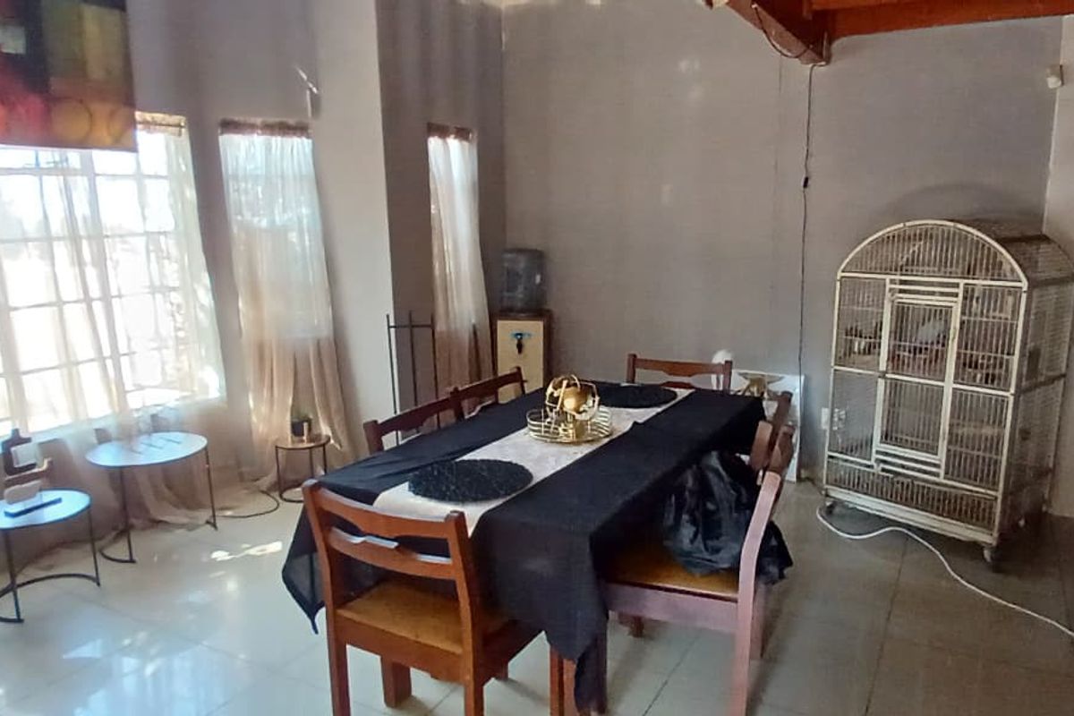 Open plan living and dining area featuring tiled flooring and large windows, seamlessly connected to a functional kitchen space.