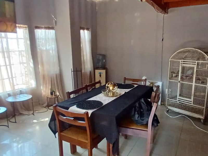 Open plan living and dining area featuring tiled flooring and large windows, seamlessly connected to a functional kitchen space.