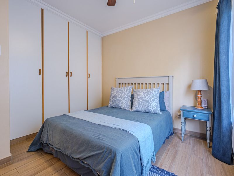 A well-maintained bedroom featuring built-in cupboards, tiled flooring, and crown molding, providing a clean and functional living space.
