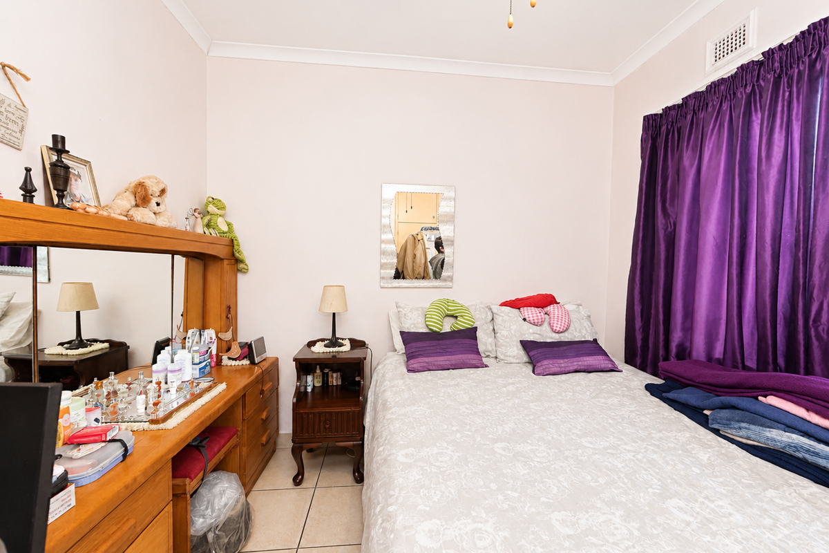 A functional bedroom featuring tiled flooring, cove cornicing, and an integrated air conditioning vent, offering a neutral base for potential interior updates.