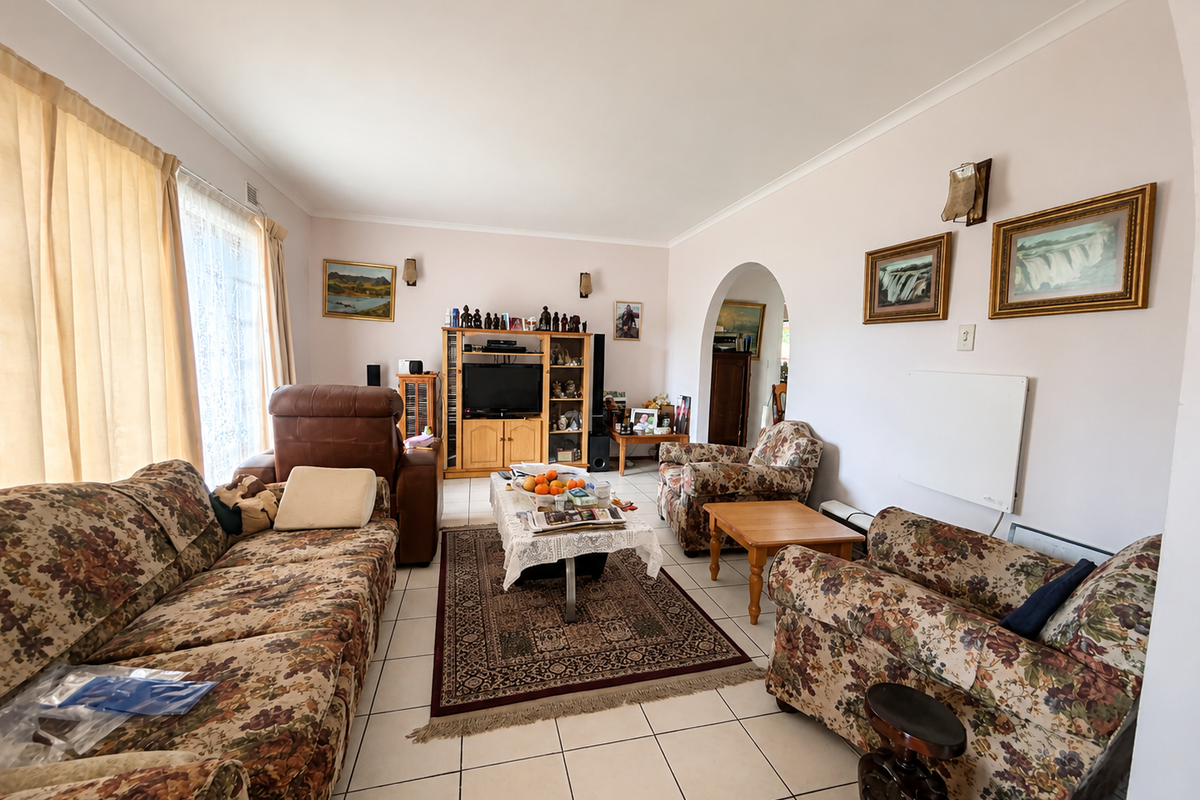 A spacious living room featuring neutral walls, tiled flooring, and a distinctive arched entryway leading to adjacent living areas.