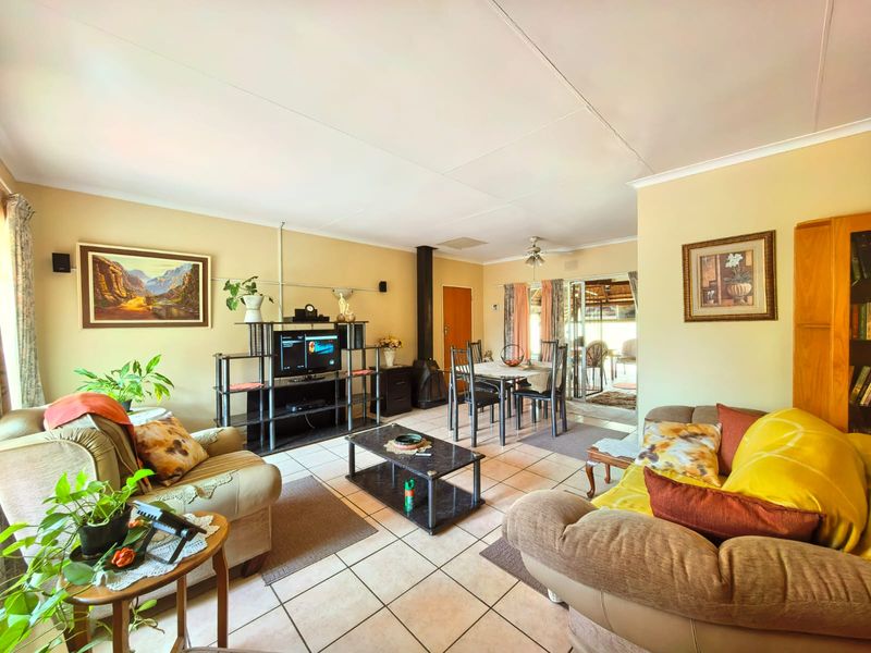 Spacious open-plan living and dining area featuring tiled flooring, a central fireplace, and sliding doors leading to an outdoor patio space.