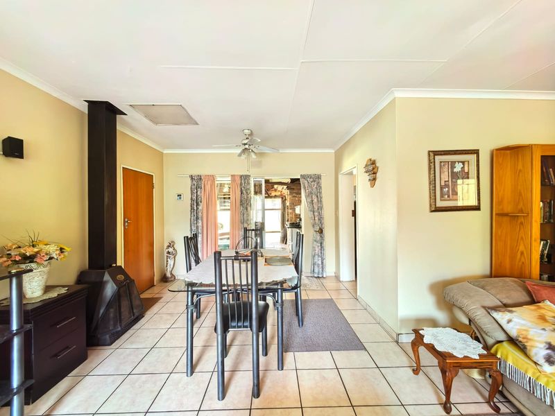 Dining area featuring tiled flooring, a freestanding fireplace, and a ceiling fan, with direct access to an outdoor space through sliding glass doors.