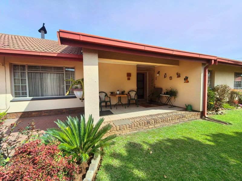 A covered patio area featuring tiled flooring and brick edging, providing a pleasant outdoor space overlooking the garden.