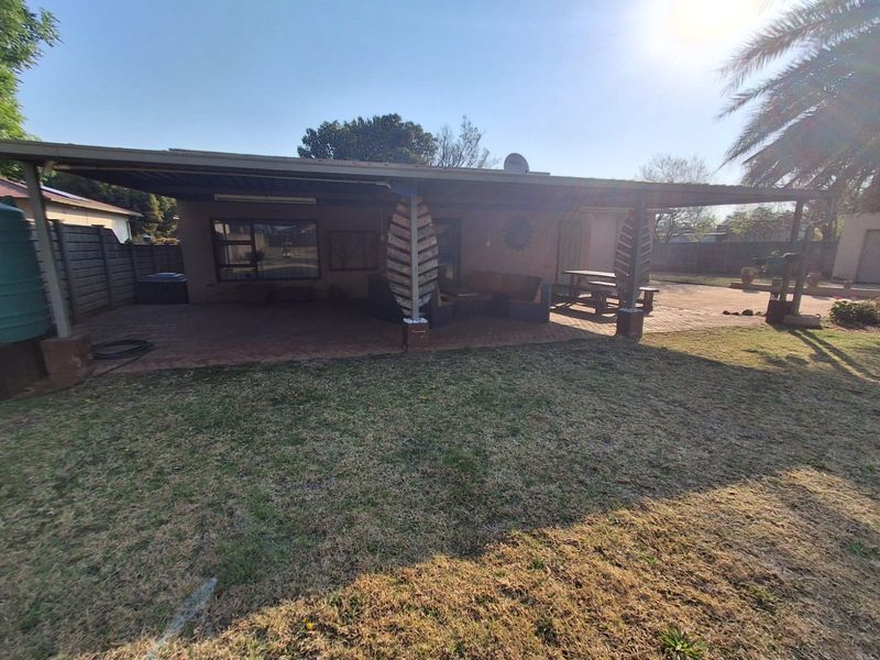 A spacious covered patio area with paved flooring and decorative support columns, overlooking the rear garden.