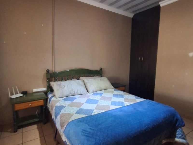 A bedroom featuring tiled flooring, a built-in wardrobe, and a coved ceiling. The room requires cosmetic updates to the walls and finishes.
