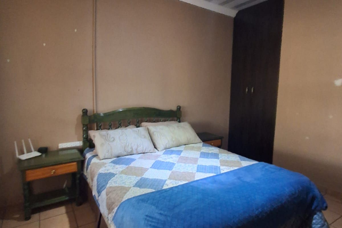 A bedroom featuring tiled flooring, a built-in wardrobe, and a coved ceiling. The room requires cosmetic updates to the walls and finishes.