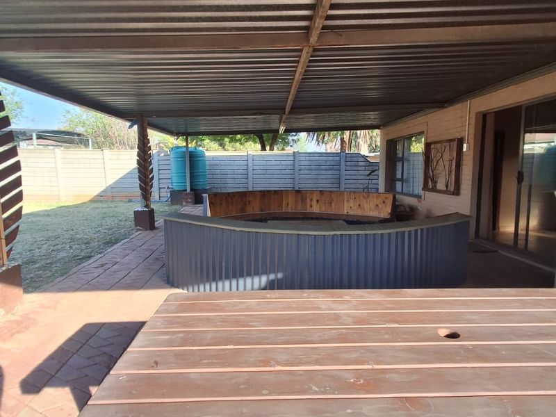 Covered outdoor patio area featuring a built-in bar counter, bench seating, and paved flooring, providing a functional space for outdoor entertaining.