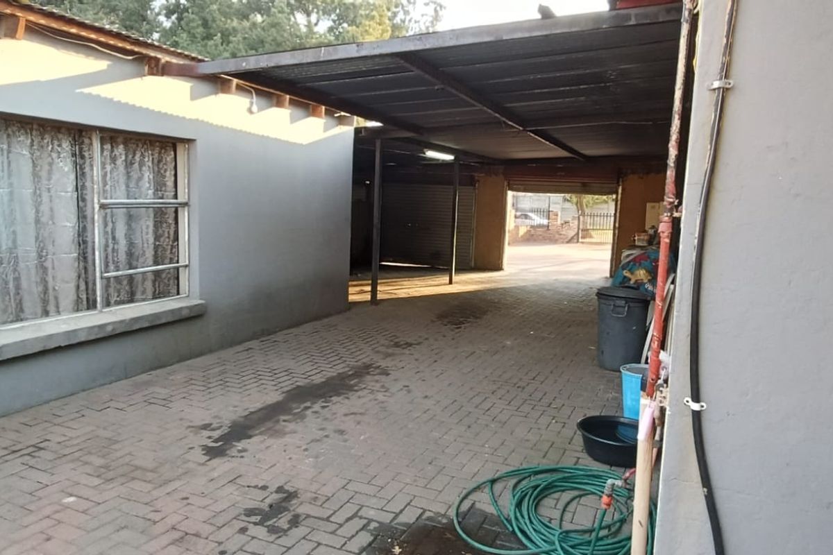 A paved rear courtyard area featuring a covered carport structure and direct access to the property exterior.