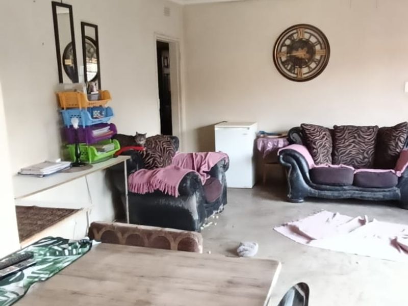 A living area featuring a ceiling fan and concrete flooring, offering a blank canvas for potential renovation and interior design updates.