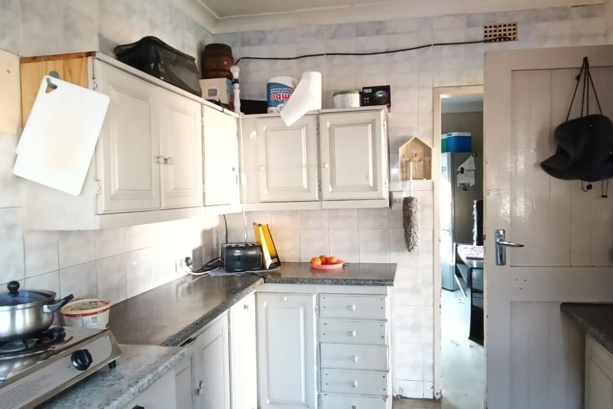 A dated kitchen featuring original cabinetry, tiled splashbacks, and a gas hob, offering significant potential for modernization and renovation.