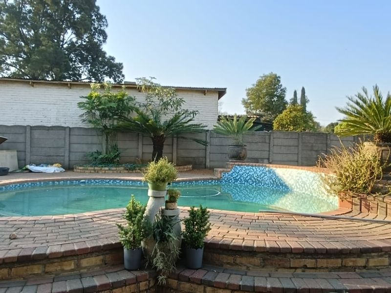 Outdoor pool area featuring a curved swimming pool with brick paved surround and perimeter precast concrete walling.