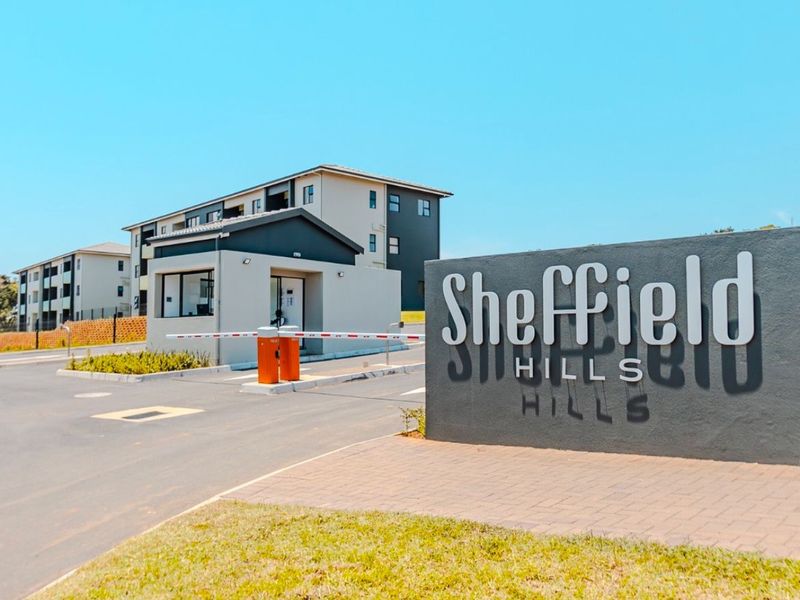 The entrance to Sheffield Hills apartment complex featuring a modern security gatehouse, boom gate access, and clear signage.