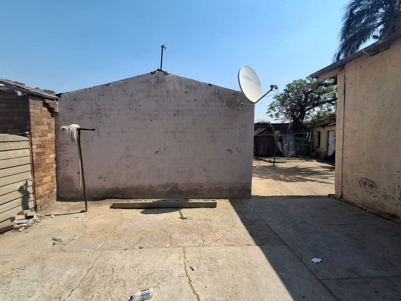 Rear exterior area featuring concrete paving and plastered brick walls with a mounted satellite dish.