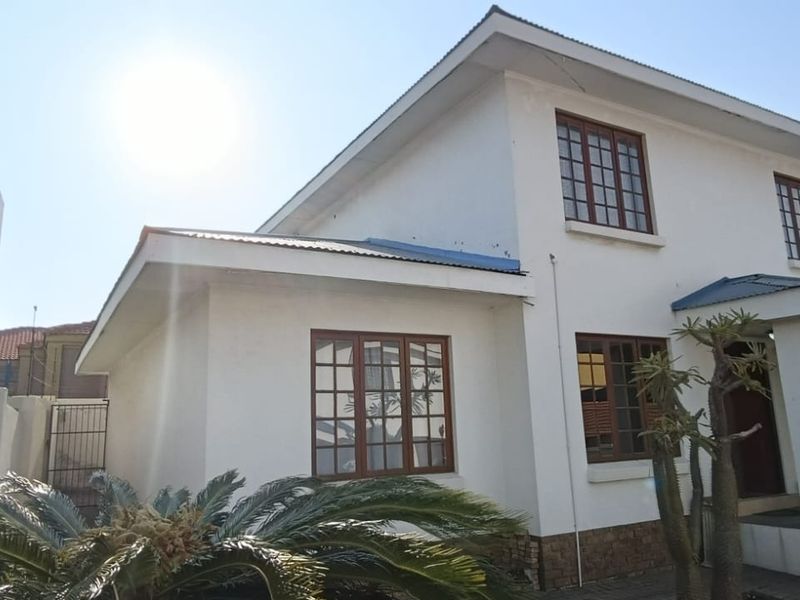Front elevation of a two-story townhouse featuring white rendered walls, timber-framed windows, and a covered entrance porch.