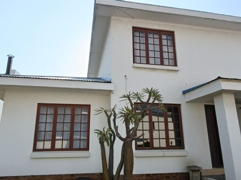 Front elevation of a two-story townhouse featuring white plastered walls, timber-framed windows, and a covered entrance porch.