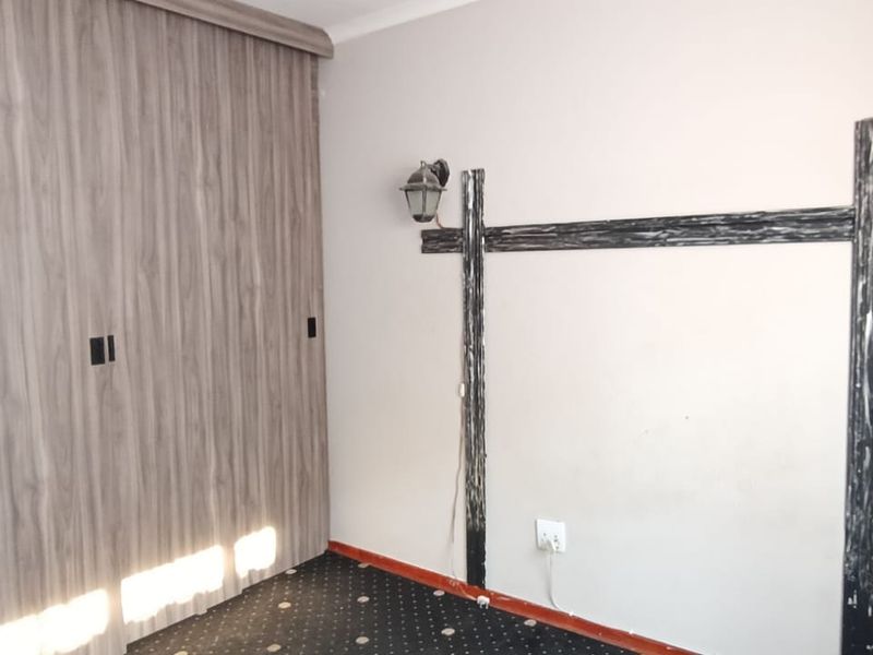 A bedroom featuring a large built-in wardrobe with wood-grain finish, carpeted flooring, and decorative wall-mounted light fixtures.
