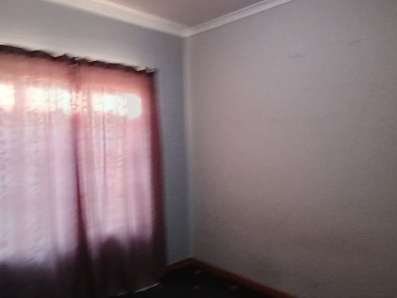 A vacant bedroom featuring neutral walls, coving, and a window with curtains, requiring minor cosmetic updates to refresh the space.
