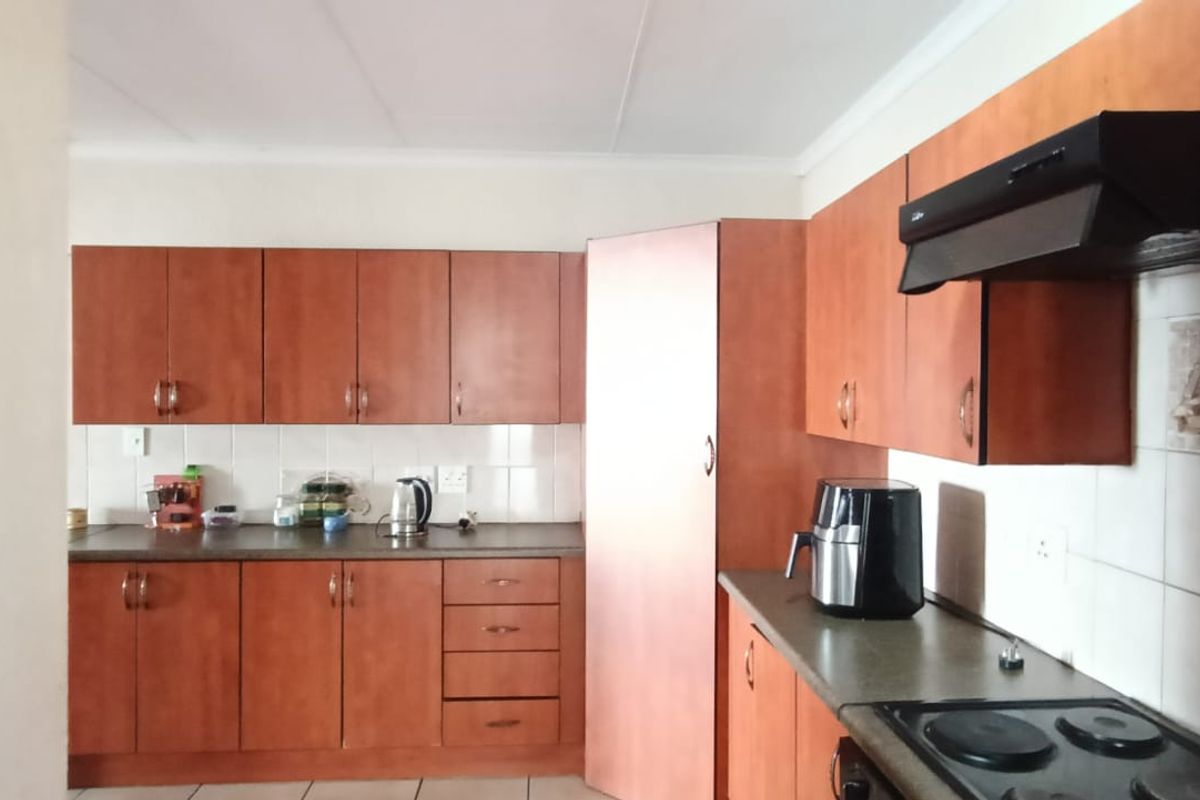 A functional kitchen featuring wood-look laminate cabinetry, tiled backsplash, and built-in cooking appliances, offering a practical layout for daily meal preparation.