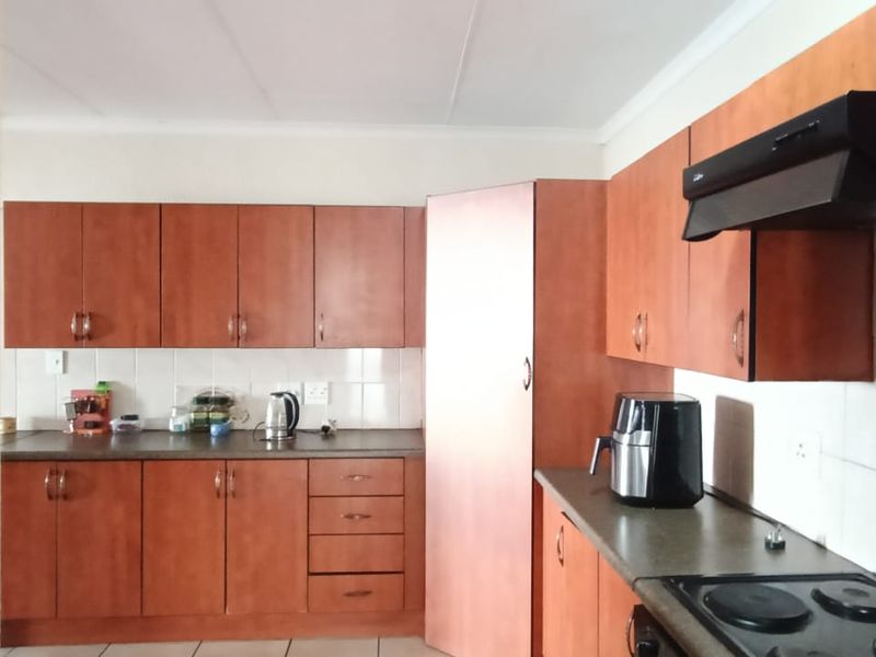 A functional kitchen featuring wood-look laminate cabinetry, tiled backsplash, and built-in cooking appliances, offering a practical layout for daily meal preparation.