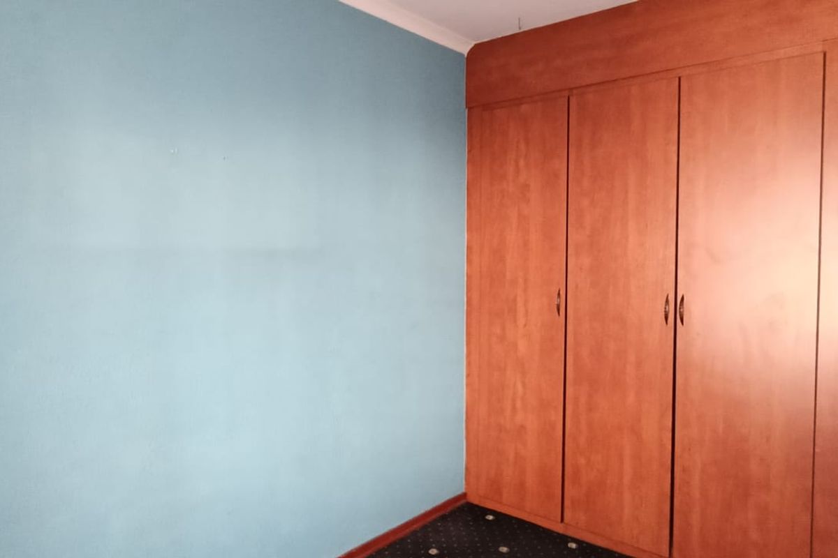 A bedroom featuring built-in wooden cupboards and a blue accent wall.