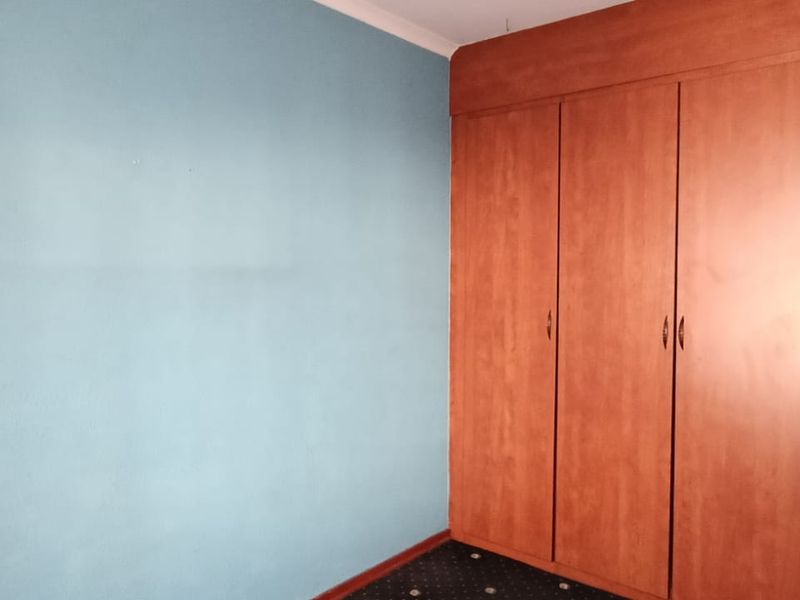 A bedroom featuring built-in wooden cupboards and a blue accent wall.