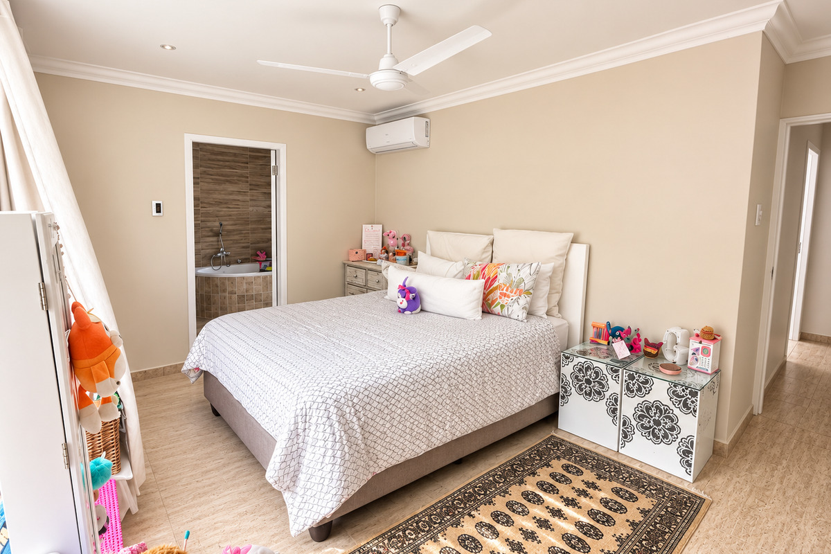 Spacious bedroom featuring tiled flooring, a ceiling fan, and a split-system air conditioner, with an adjoining en-suite bathroom visible.