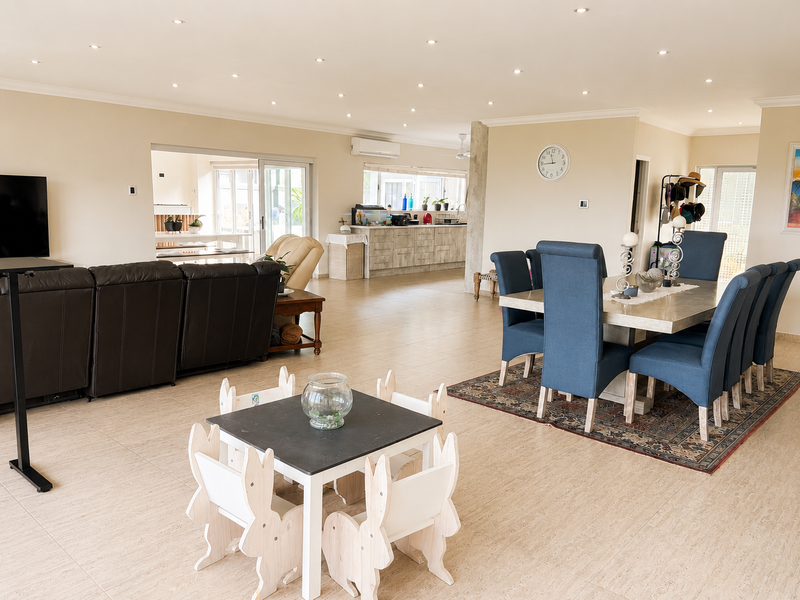 Spacious open-plan living and dining area featuring tiled floors, recessed lighting, and seamless flow to the kitchen and outdoor patio.