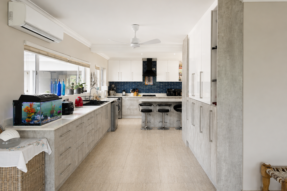 Modern kitchen featuring extensive built-in cabinetry, stone countertops, a blue subway tile backsplash, and integrated appliances, complemented by tiled flooring and air conditioning.