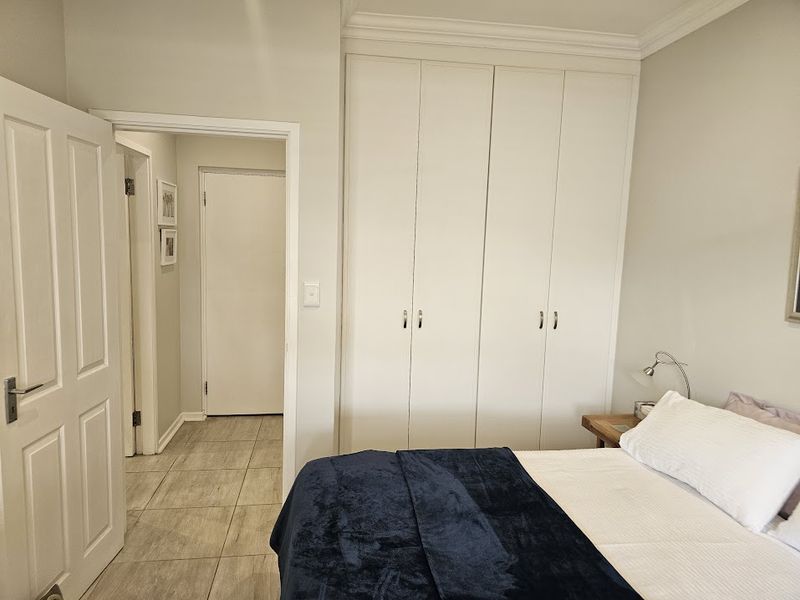A well-maintained bedroom featuring neutral walls, tiled flooring, and ample built-in cupboard storage space.