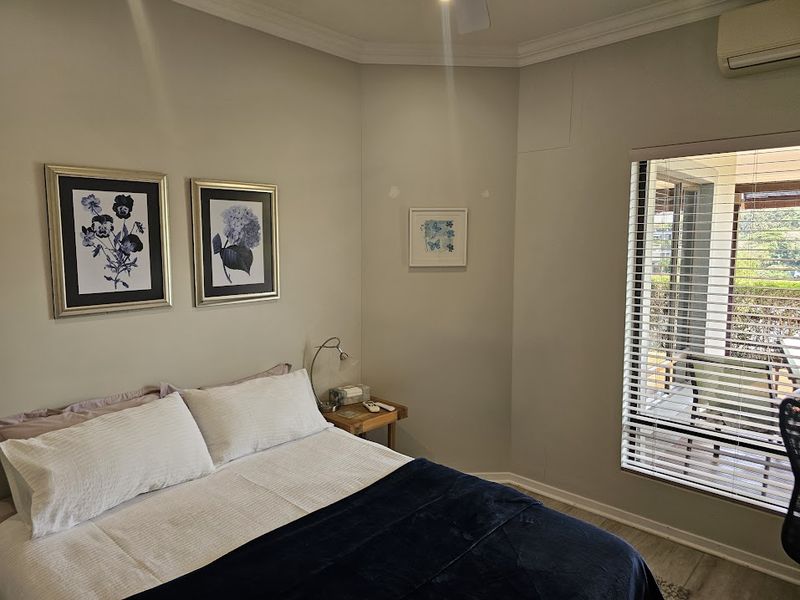A bedroom featuring a ceiling fan, split-system air conditioning, and a sliding glass door with venetian blinds providing access to an outdoor area.