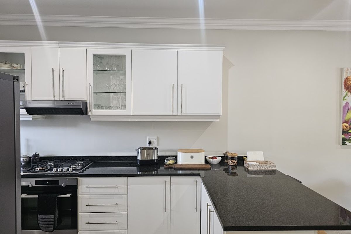 Modern kitchen featuring white cabinetry, granite countertops, integrated gas cooktop, and built-in oven with a clean, functional layout.