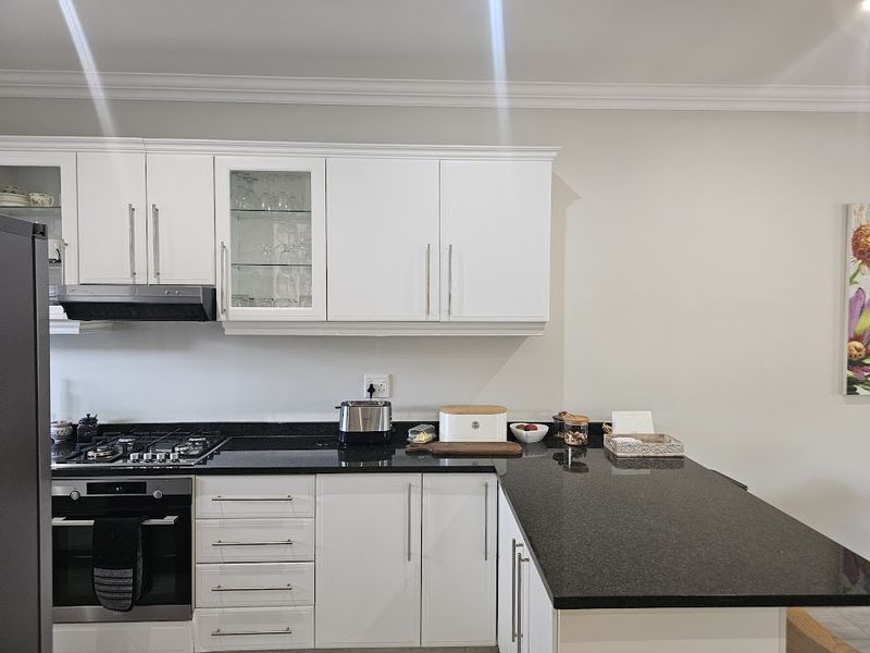 Modern kitchen featuring white cabinetry, granite countertops, integrated gas cooktop, and built-in oven with a clean, functional layout.