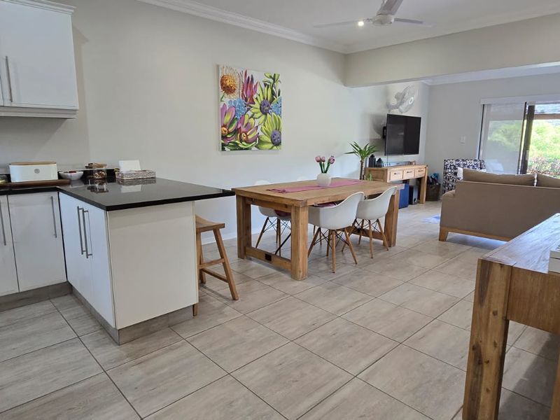 Open plan living area featuring a modern kitchen with granite countertops, tiled flooring, and seamless flow to the dining and lounge space.