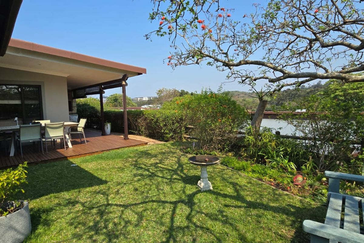 A well-maintained rear garden featuring a timber deck, covered patio area, and established landscaping with views of the surrounding area.