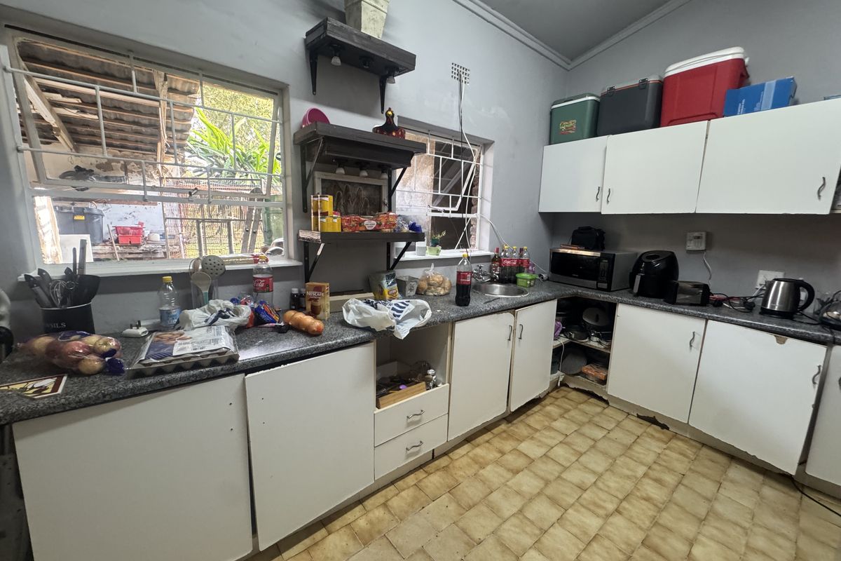 A functional kitchen featuring laminate countertops, built-in cabinetry, and a stainless steel sink, requiring cosmetic updates to improve its overall condition.