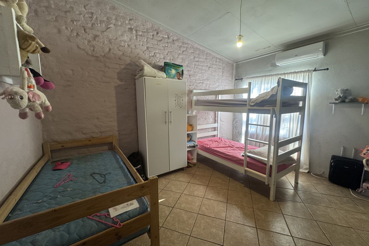 A bedroom featuring tiled flooring, a textured brick wall, and an installed air conditioning unit.