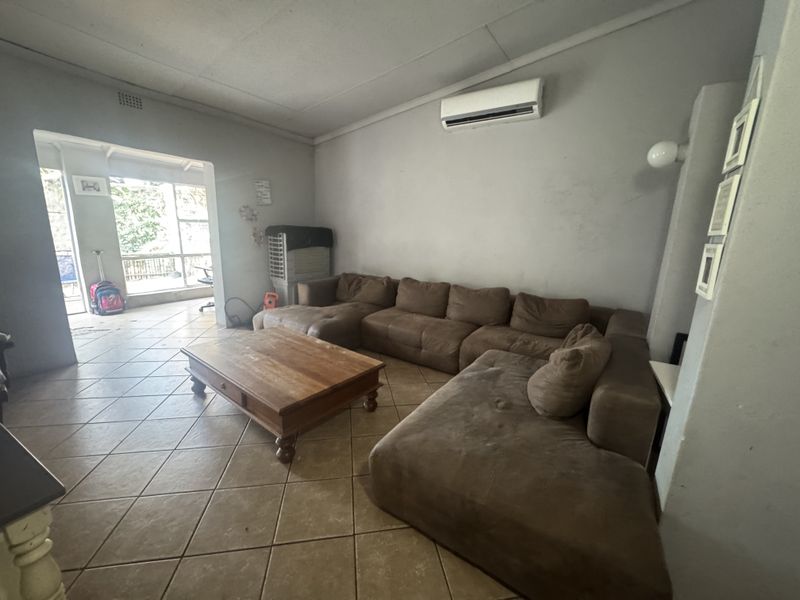 Spacious living room featuring ceramic floor tiles and a wall-mounted split-system air conditioner, with direct access to an adjoining patio area.