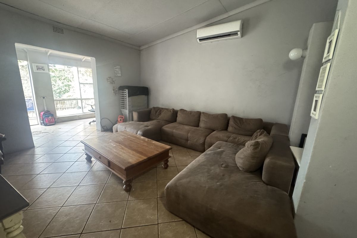 Spacious living room featuring ceramic floor tiles and a wall-mounted split-system air conditioner, with direct access to an adjoining patio area.