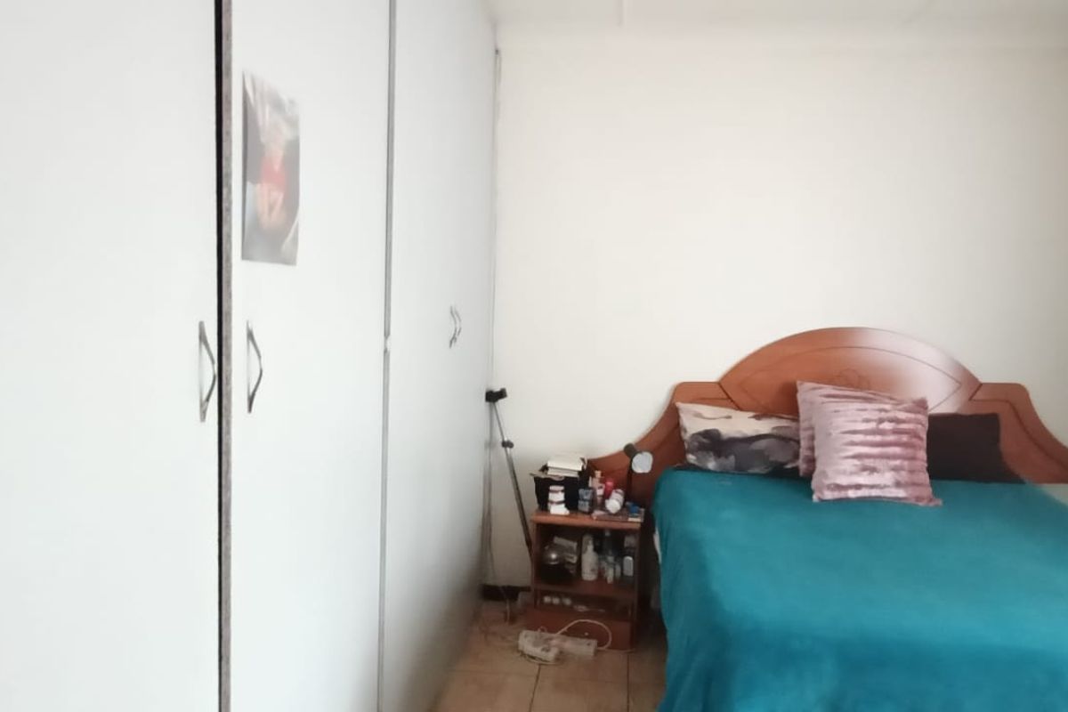 A bedroom featuring built-in cupboards and tiled flooring.