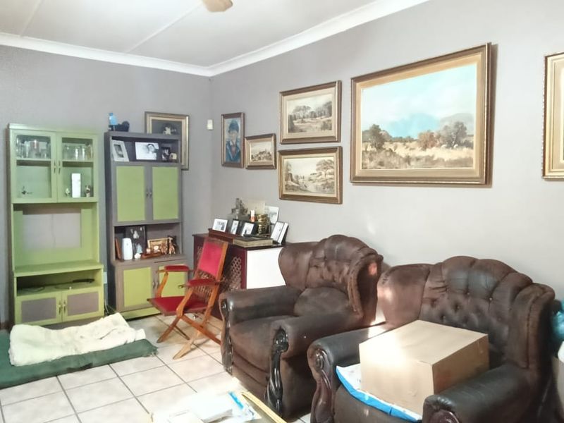 A living room featuring tiled flooring and cove cornice detailing, providing a neutral base for potential interior updates.