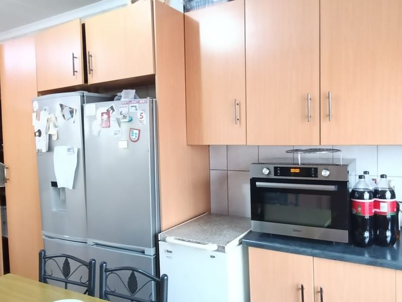 A functional kitchen featuring light wood-tone cabinetry, laminate countertops, and a tiled backsplash, providing ample storage and workspace.